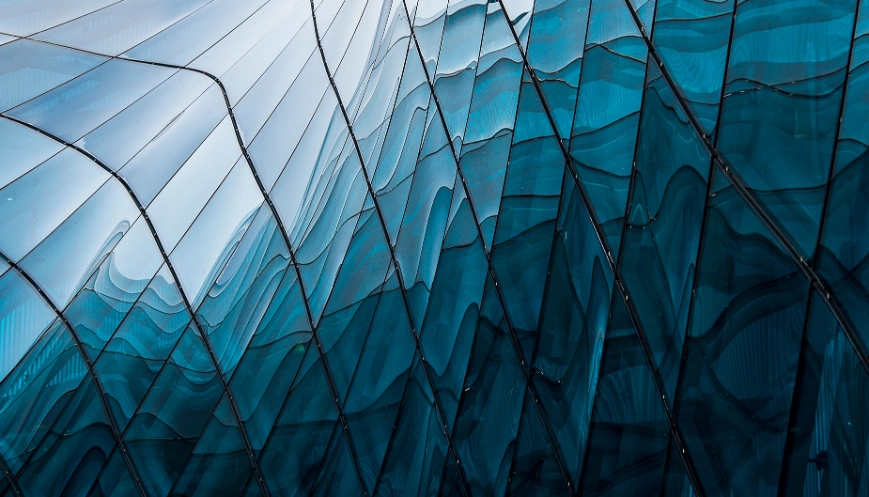 |Reflection of blue sky on building glass windows with curve lines.